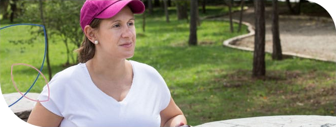 mulher vestindo camiseta branca e boné rosa praticando atividade física no parque
