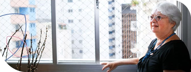 senhora vestindo blusa preta apoiada na janela de casa