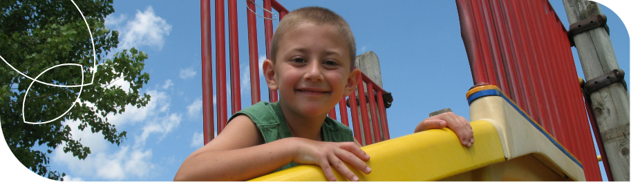 Menino sorrindo e brincando no escorregador de um parque