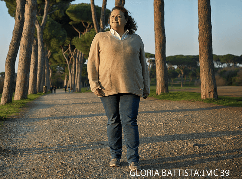 Mulher adulta caminhando sozinha em parque arborizado, promovendo bem-estar e saúde com atividade física
