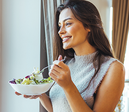 mulher sorrindo segurando um prato de salada
